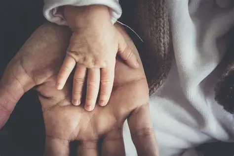 La mano de un bebé apoyada sobre la mano de un adulto